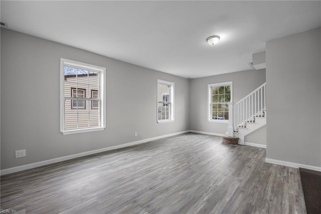 empty room featuring stairway, baseboards, and wood finished floors