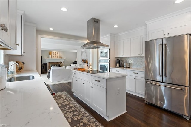 kitchen with a kitchen island, appliances with stainless steel finishes, island range hood, white cabinets, and a sink