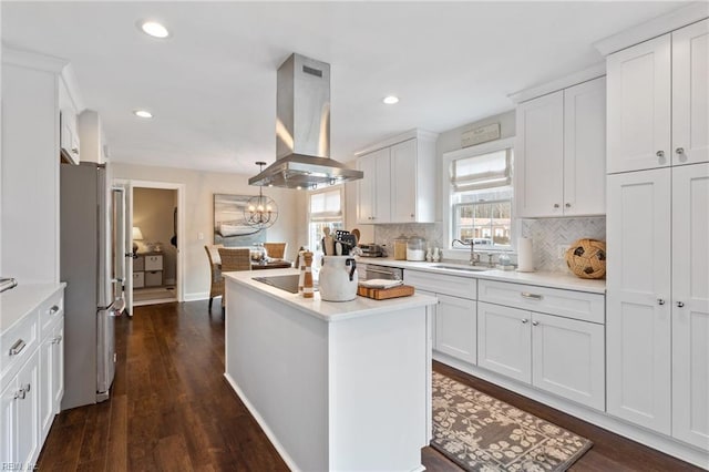 kitchen featuring island range hood, freestanding refrigerator, a sink, white cabinets, and a center island