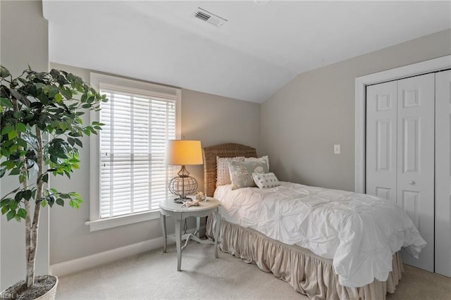 carpeted bedroom with lofted ceiling, baseboards, visible vents, and a closet