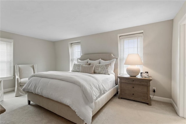 bedroom featuring multiple windows, light colored carpet, and baseboards