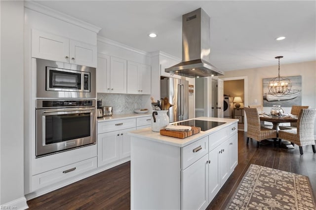 kitchen with island exhaust hood, washer and dryer, a kitchen island, dark wood finished floors, and appliances with stainless steel finishes