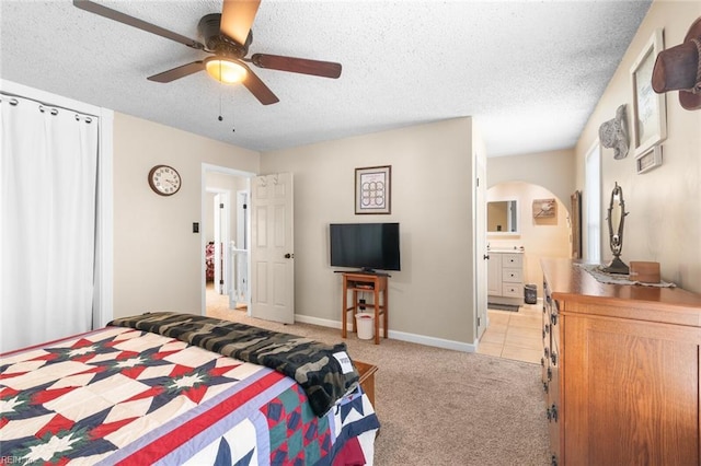 bedroom featuring light carpet, arched walkways, and a textured ceiling