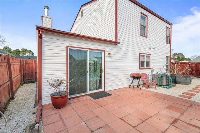 back of property featuring a fenced backyard, a chimney, and a patio area