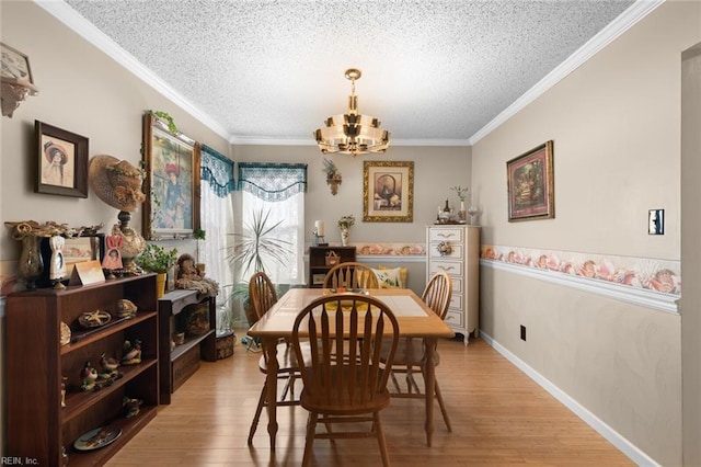 dining room with a chandelier, a textured ceiling, light wood-type flooring, and ornamental molding