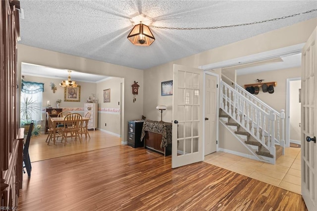 interior space featuring stairs, wood finished floors, baseboards, and a textured ceiling