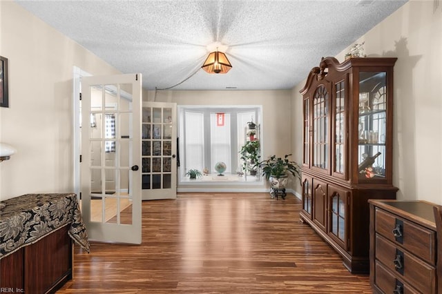 foyer featuring baseboards, a textured ceiling, and wood finished floors