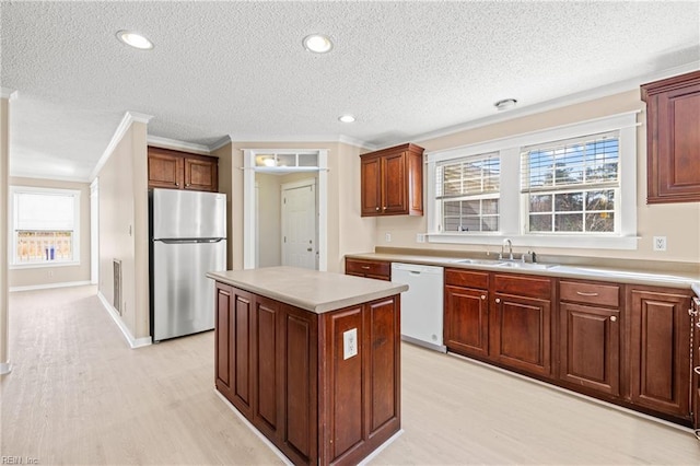 kitchen featuring light wood finished floors, a kitchen island, dishwasher, freestanding refrigerator, and a sink