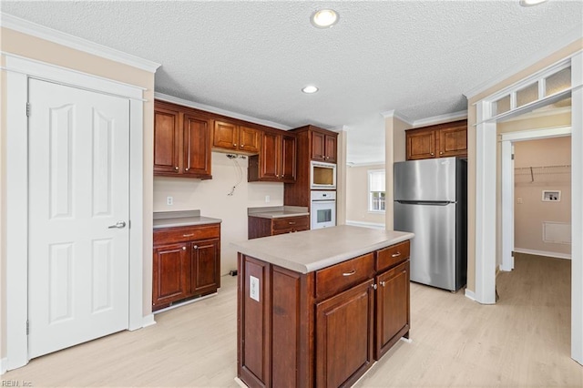 kitchen featuring light wood finished floors, a center island, stainless steel appliances, and ornamental molding