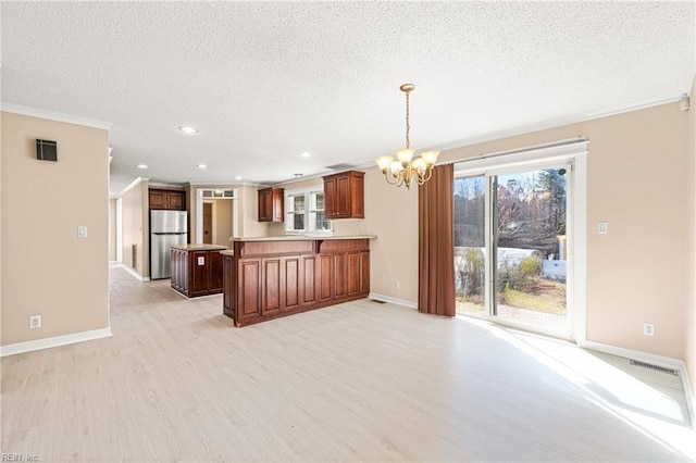 kitchen featuring a notable chandelier, light wood-style flooring, a textured ceiling, freestanding refrigerator, and a peninsula