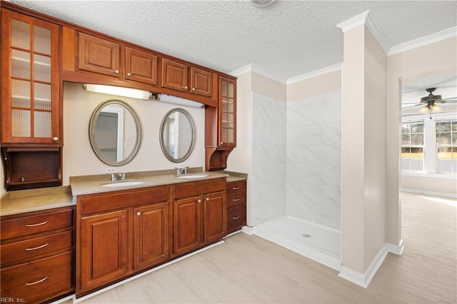 bathroom featuring a sink, wood finished floors, ornamental molding, and a ceiling fan