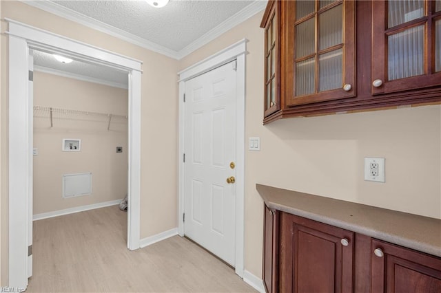 laundry room featuring hookup for an electric dryer, washer hookup, a textured ceiling, crown molding, and light wood-type flooring