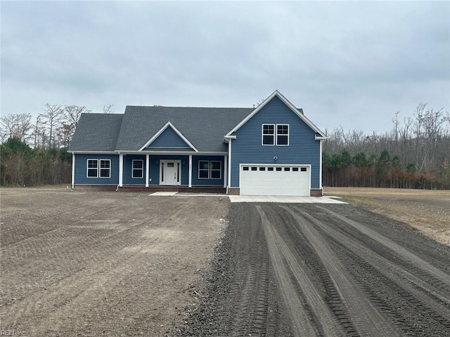 view of front of house with an attached garage, covered porch, and dirt driveway