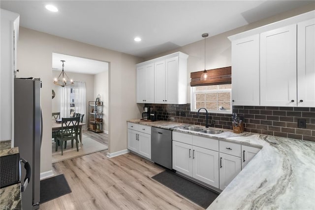 kitchen featuring light stone counters, light wood-style flooring, appliances with stainless steel finishes, white cabinets, and a sink