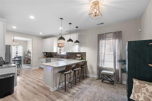 kitchen with an inviting chandelier, a breakfast bar area, tasteful backsplash, and white cabinets