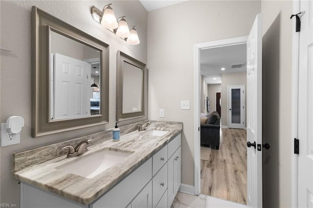 ensuite bathroom featuring a sink, baseboards, ensuite bathroom, and double vanity