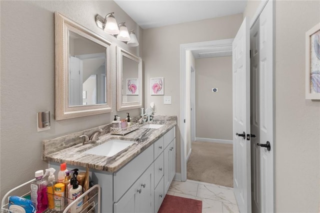 bathroom with a sink, baseboards, marble finish floor, and double vanity