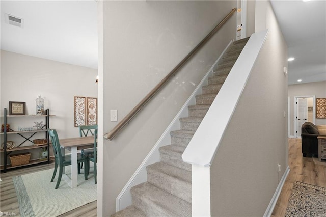 stairway featuring recessed lighting, wood finished floors, visible vents, and baseboards