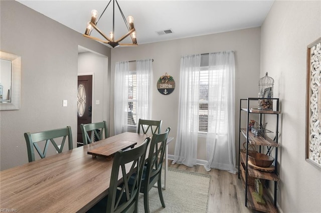 dining space featuring light wood-type flooring, visible vents, baseboards, and a notable chandelier