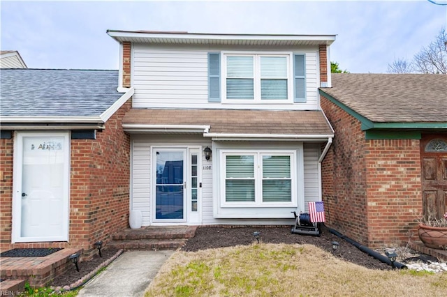 exterior space with brick siding and roof with shingles