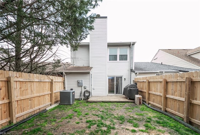 back of house with central air condition unit, a fenced backyard, and a chimney