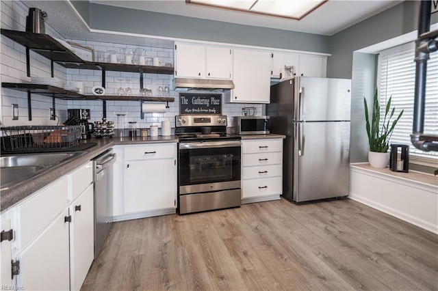 kitchen featuring light wood finished floors, under cabinet range hood, appliances with stainless steel finishes, white cabinets, and open shelves