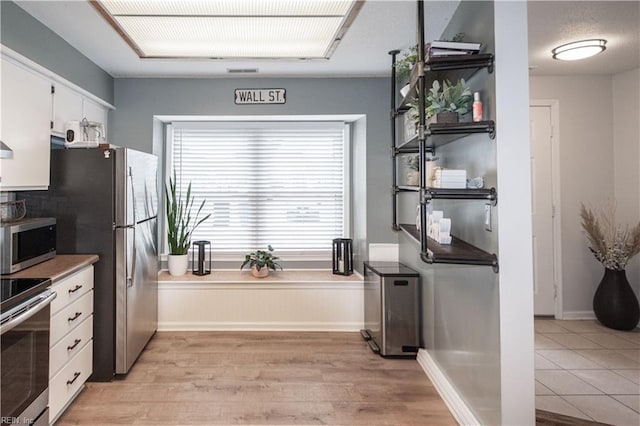 kitchen with visible vents, baseboards, light wood-style flooring, stainless steel appliances, and white cabinetry