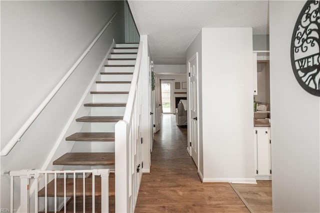 stairs featuring a textured ceiling and wood finished floors