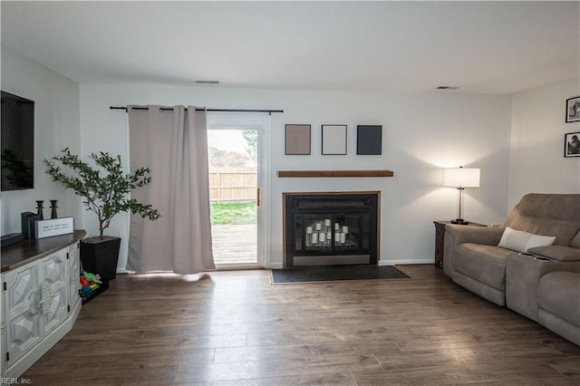 living area with a fireplace with flush hearth, wood finished floors, and visible vents