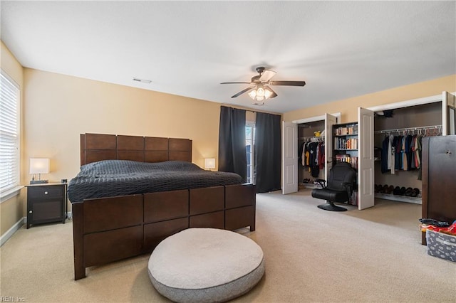 bedroom with baseboards, visible vents, ceiling fan, multiple closets, and light colored carpet