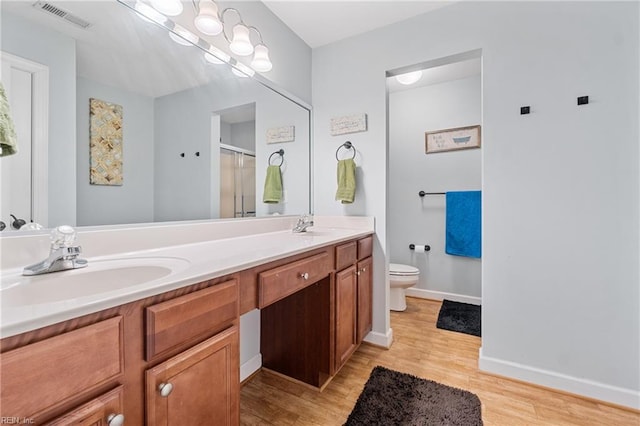 full bath with wood finished floors, visible vents, double vanity, a sink, and a shower stall