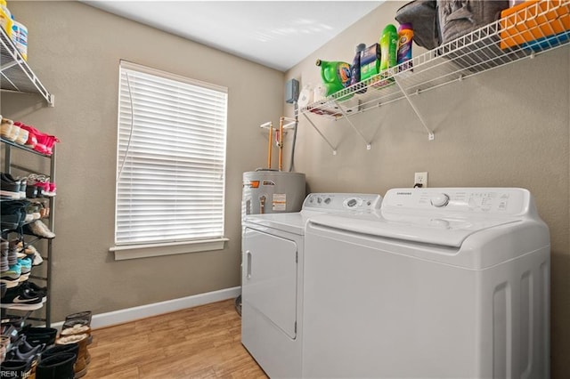 washroom featuring light wood finished floors, baseboards, washer and clothes dryer, water heater, and laundry area