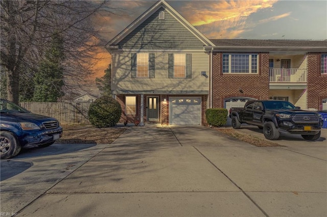 view of front of home featuring brick siding, driveway, a garage, and fence