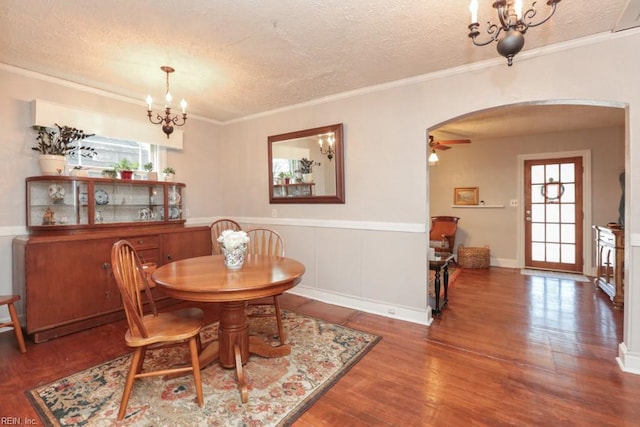 dining area with arched walkways, a textured ceiling, and wood finished floors