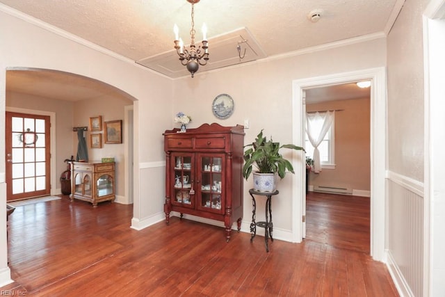 corridor featuring a baseboard radiator, ornamental molding, arched walkways, a textured ceiling, and wood-type flooring