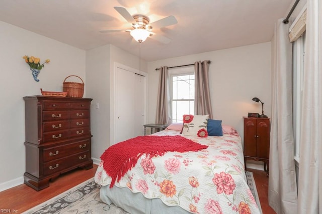 bedroom featuring a closet, baseboards, ceiling fan, and wood finished floors