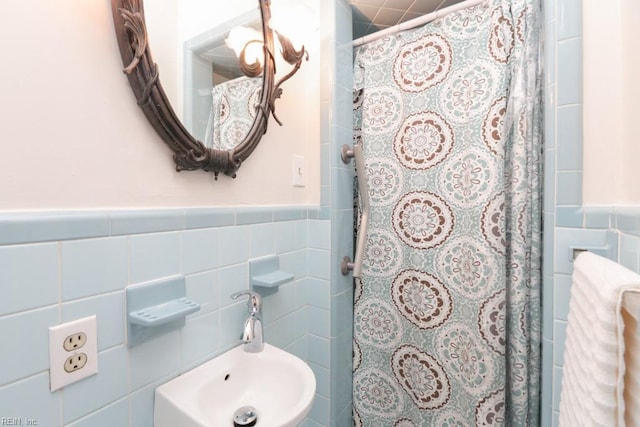 full bath with wainscoting, curtained shower, tile walls, and a sink