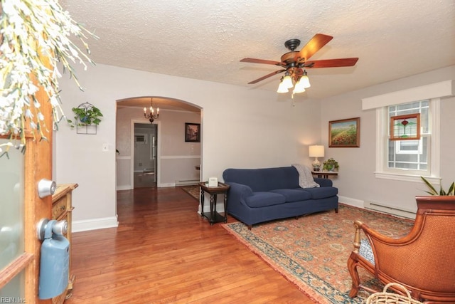 living room with a baseboard heating unit, baseboard heating, arched walkways, and light wood finished floors