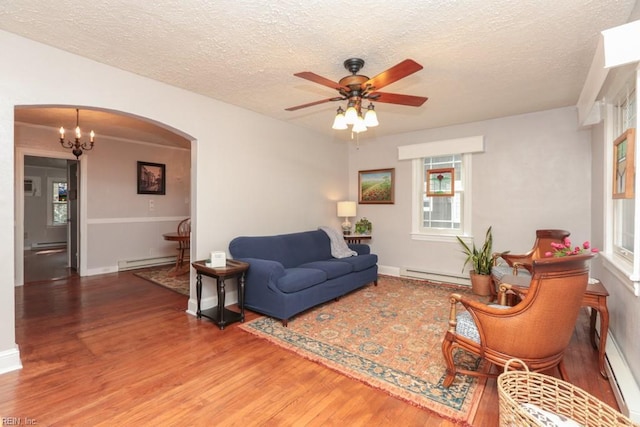 living area featuring a baseboard heating unit, arched walkways, wood finished floors, and a baseboard radiator