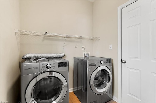 washroom featuring laundry area, washer and dryer, light wood-type flooring, and baseboards