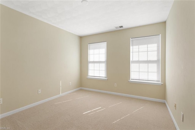 spare room with light colored carpet, baseboards, and visible vents