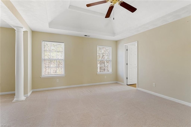 spare room featuring a tray ceiling, light carpet, visible vents, and ornate columns