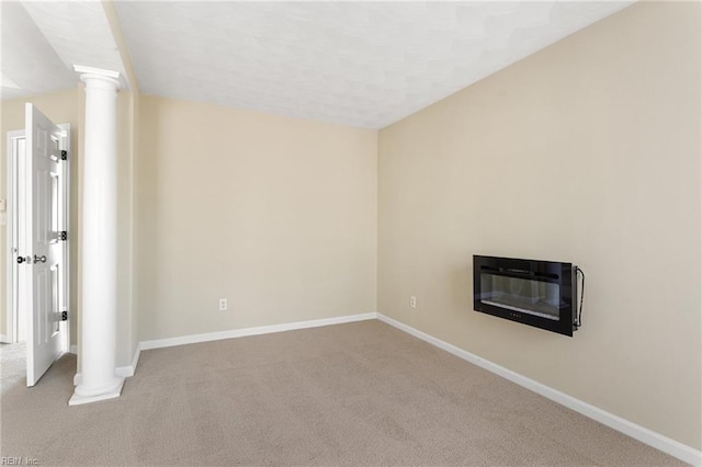 interior space with decorative columns, baseboards, a glass covered fireplace, and carpet flooring