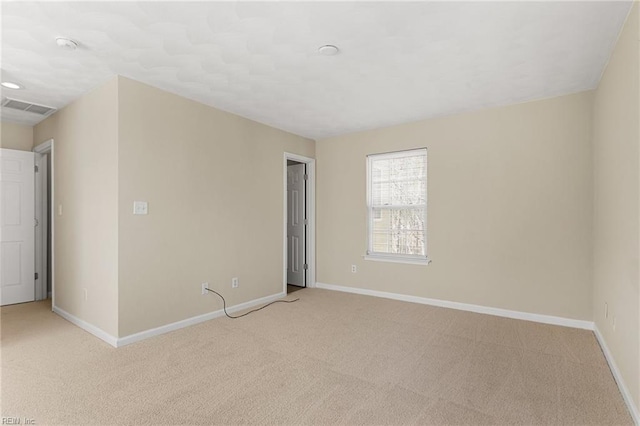 spare room with visible vents, light carpet, and baseboards