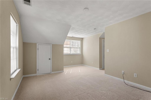 bonus room with visible vents, baseboards, light colored carpet, and lofted ceiling