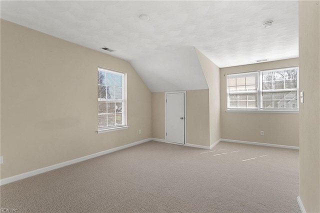 additional living space with carpet, lofted ceiling, baseboards, and visible vents