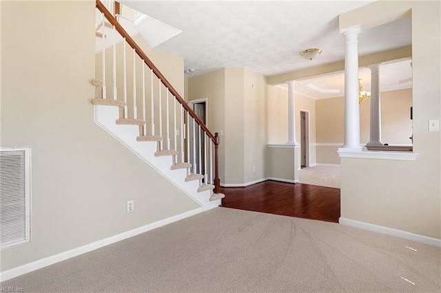 carpeted foyer with stairway, baseboards, visible vents, and ornate columns