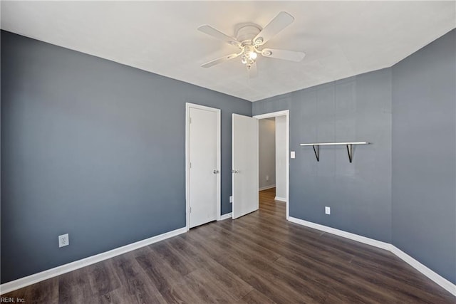 spare room with a ceiling fan, dark wood-type flooring, and baseboards