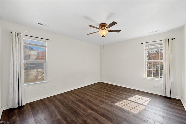 empty room with dark wood finished floors, visible vents, ceiling fan, and baseboards