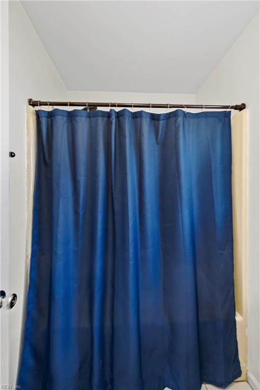 full bathroom featuring a shower with shower curtain and lofted ceiling